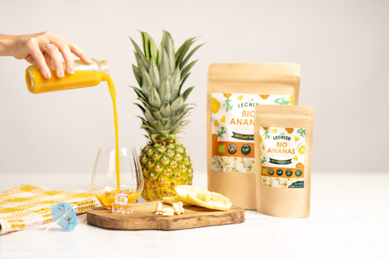 Gefriergetrocknete Ananas Packung neben einer Ananas und Ananassmoothie