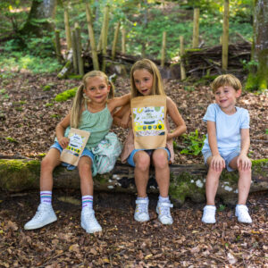 3 Kinder mit gefriergetrockneten Jackfruit auf einem Baumstamm