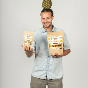 Mann mit gefriergetrockneter Ananas in den Händen und Ananas auf dem Kopf